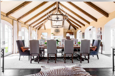 Example of a huge mountain style dark wood floor and brown floor dining room design in Nashville with beige walls, a standard fireplace and a stone fireplace