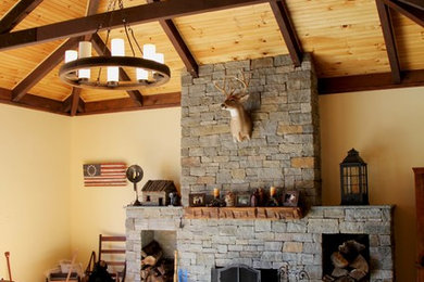 Cette photo montre une grande salle de séjour montagne ouverte avec un mur beige, un sol en bois brun, une cheminée standard et un manteau de cheminée en pierre.
