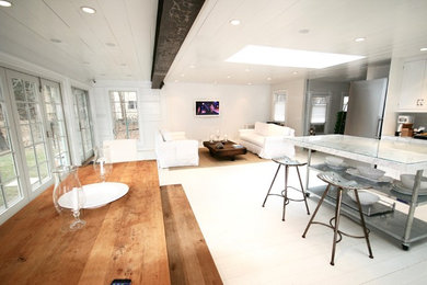Example of a classic light wood floor and white floor family room design in New York with white walls, no fireplace and a wall-mounted tv