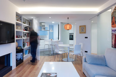 Ejemplo de sala de estar abierta contemporánea de tamaño medio con paredes blancas, suelo de madera en tonos medios, todas las chimeneas y televisor colgado en la pared