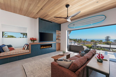 Family room - mid-sized coastal open concept ceramic tile, beige floor and wood ceiling family room idea in Santa Barbara with white walls, a ribbon fireplace, a tile fireplace and a wall-mounted tv