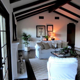 Example of a mid-sized tuscan open concept dark wood floor and brown floor family room design in Santa Barbara with white walls, a standard fireplace and a concrete fireplace