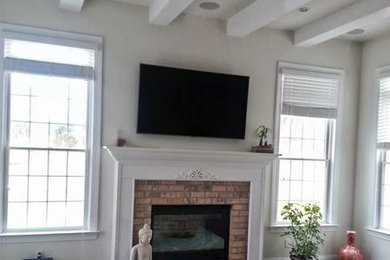 Inspiration for a medium tone wood floor family room remodel in New York with white walls, a standard fireplace, a brick fireplace and a wall-mounted tv