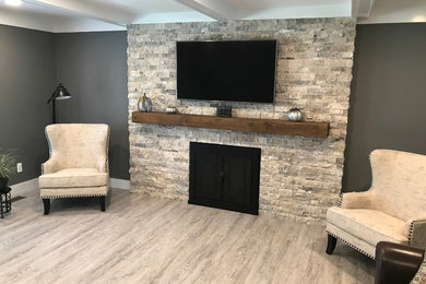 Inspiration for a shabby-chic style laminate floor and gray floor family room remodel in Detroit with gray walls, a standard fireplace, a stone fireplace and a wall-mounted tv