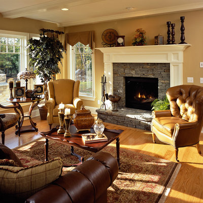Family room - traditional medium tone wood floor family room idea in New York with beige walls, a standard fireplace, a stone fireplace and no tv
