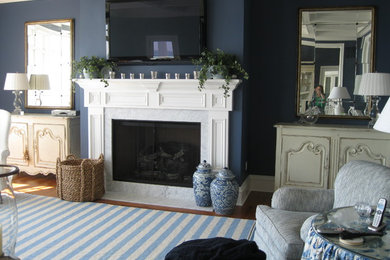 他の地域にある広いトランジショナルスタイルのおしゃれな独立型ファミリールーム (青い壁、淡色無垢フローリング、標準型暖炉、石材の暖炉まわり、壁掛け型テレビ) の写真