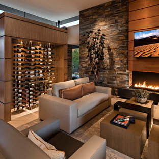 Modelo de sala de estar abierta, de estilo americano, grande, con paredes multicolor, suelo de baldosas de porcelana, chimenea tradicional, marco de chimenea de piedra, televisor colgado en la pared y suelo beige
