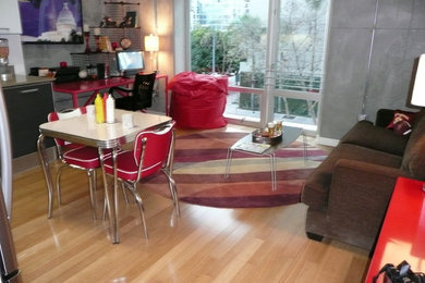 Modelo de sala de estar abierta minimalista pequeña con paredes grises, suelo de madera clara y televisor colgado en la pared