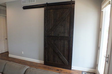 Modelo de sala de estar abierta actual de tamaño medio con paredes grises y suelo de madera oscura