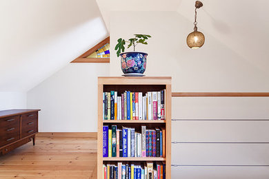 Example of a small trendy loft-style light wood floor and beige floor family room library design in Portland Maine with white walls, no tv and no fireplace