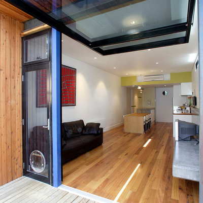 Example of a trendy open concept medium tone wood floor family room design in Melbourne with white walls