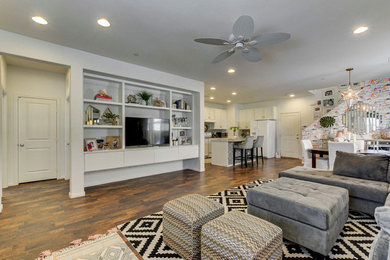 Ejemplo de sala de estar abierta contemporánea de tamaño medio sin chimenea con paredes blancas, suelo laminado, televisor independiente y suelo marrón