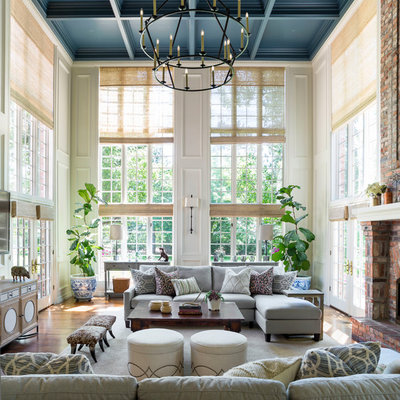 Inspiration for a huge timeless open concept medium tone wood floor and brown floor family room remodel in Denver with beige walls, a standard fireplace, a brick fireplace and a wall-mounted tv