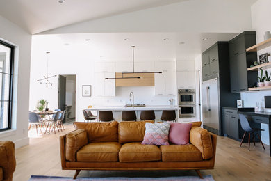 Imagen de sala de estar abierta moderna grande con paredes blancas, suelo de madera clara, todas las chimeneas, marco de chimenea de metal, televisor colgado en la pared y suelo beige
