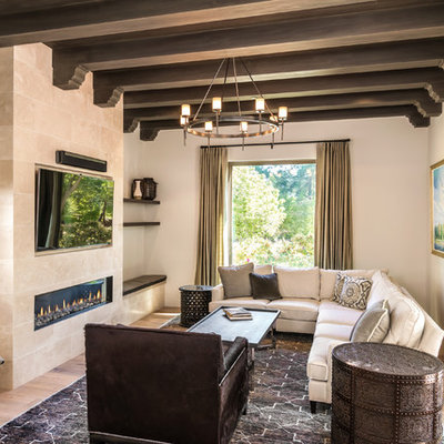 Family room - mediterranean open concept light wood floor and beige floor family room idea in San Francisco with beige walls, a ribbon fireplace, a stone fireplace and a wall-mounted tv
