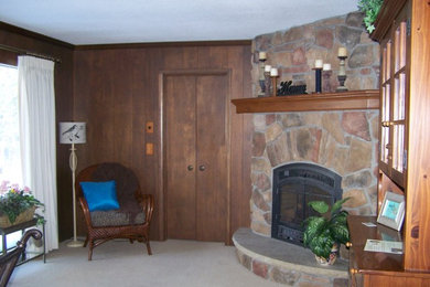 Modelo de sala de estar con biblioteca cerrada tradicional pequeña sin televisor con paredes marrones, moqueta, chimenea de esquina y marco de chimenea de piedra