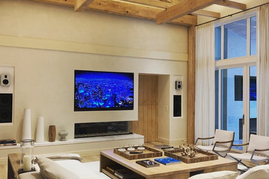 Example of a beach style family room design in New York with beige walls, a ribbon fireplace and a wall-mounted tv
