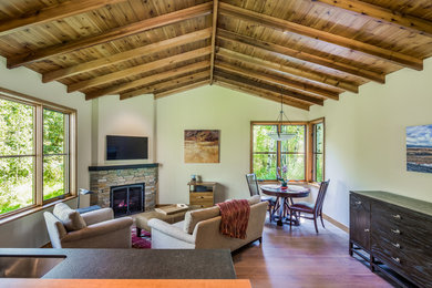 Large mountain style enclosed medium tone wood floor and brown floor family room photo in Other with beige walls, a corner fireplace, a stone fireplace and a wall-mounted tv