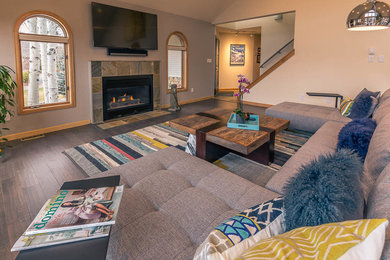 Example of a mid-sized trendy enclosed dark wood floor and brown floor family room design in Denver with brown walls, a standard fireplace, a stone fireplace and a wall-mounted tv