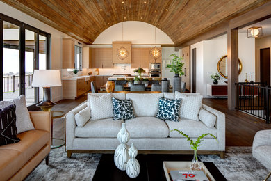 Modelo de sala de estar abierta contemporánea grande con paredes blancas, suelo de madera en tonos medios, todas las chimeneas, marco de chimenea de piedra, televisor colgado en la pared, suelo marrón y alfombra