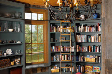 Imagen de sala de estar con biblioteca cerrada de estilo de casa de campo sin chimenea con paredes grises y suelo de madera en tonos medios