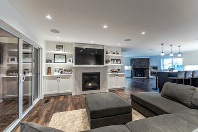 Example of a large transitional open concept dark wood floor and brown floor family room design in Vancouver with white walls, a standard fireplace, a wall-mounted tv and a stone fireplace