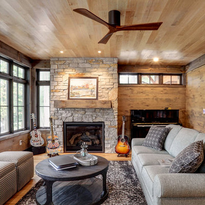 Inspiration for a rustic medium tone wood floor and brown floor family room remodel in Other with a music area, brown walls, a standard fireplace and a stone fireplace
