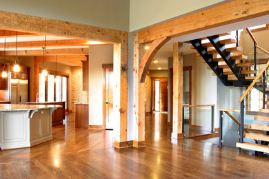 Diseño de sala de estar abierta de estilo americano grande con paredes beige y suelo de madera en tonos medios