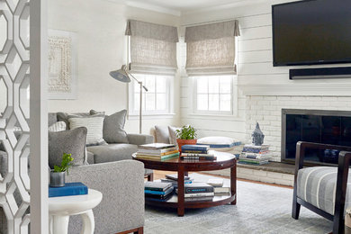 Inspiration for a mid-sized transitional enclosed medium tone wood floor and brown floor family room remodel in New York with white walls, a wall-mounted tv, a standard fireplace and a brick fireplace