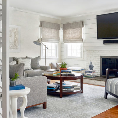 Inspiration for a mid-sized transitional enclosed medium tone wood floor and brown floor family room remodel in New York with white walls, a wall-mounted tv, a standard fireplace and a brick fireplace