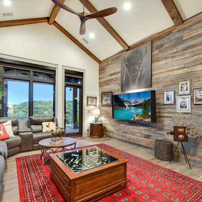 Example of a mountain style enclosed light wood floor and beige floor family room design in Austin with beige walls and a wall-mounted tv