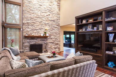 Example of a minimalist medium tone wood floor and brown floor family room design in Chicago with a standard fireplace, a media wall and a stone fireplace