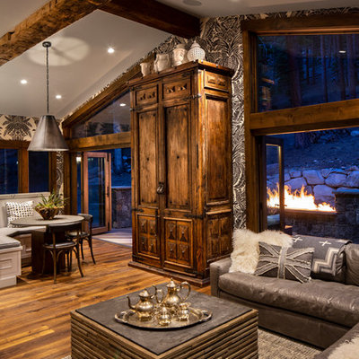 Example of a mid-sized mountain style open concept medium tone wood floor and brown floor family room design in Other with gray walls, no fireplace and a wall-mounted tv