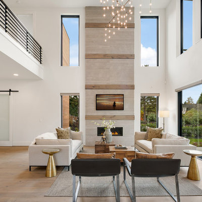 Example of a large trendy open concept medium tone wood floor and beige floor family room design in Seattle with white walls, a standard fireplace, a wall-mounted tv and a stone fireplace