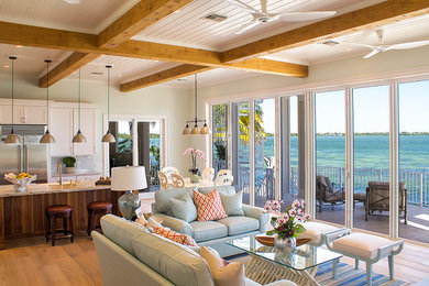 Diseño de sala de estar con barra de bar abierta costera grande sin chimenea y televisor con paredes verdes, suelo de madera clara y suelo beige