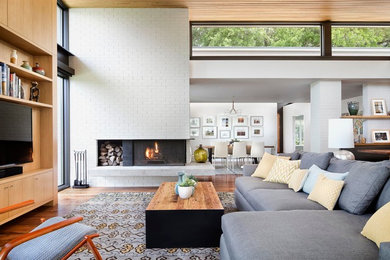 Immagine di un soggiorno contemporaneo aperto con pavimento in legno massello medio, camino ad angolo, parete attrezzata e tappeto