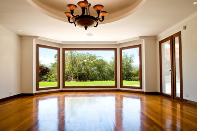 Foto de sala de estar cerrada clásica grande sin chimenea con paredes beige, suelo de madera en tonos medios y suelo marrón