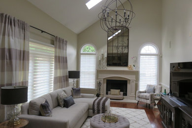 Modelo de sala de estar abierta clásica renovada de tamaño medio con paredes beige, suelo de madera en tonos medios, todas las chimeneas y marco de chimenea de hormigón