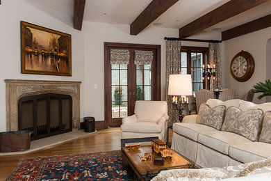 Diseño de sala de estar abierta clásica grande con paredes blancas, suelo de madera oscura, todas las chimeneas y marco de chimenea de piedra