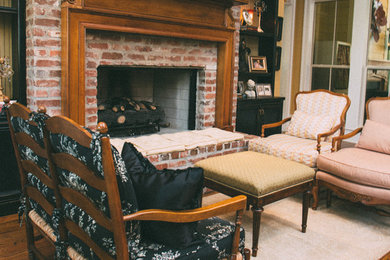 Example of a mid-sized classic open concept medium tone wood floor family room design in New Orleans with yellow walls, a standard fireplace, a brick fireplace and no tv