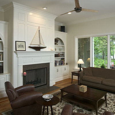 Inspiration for a timeless medium tone wood floor family room remodel in Charlotte with beige walls, a standard fireplace and no tv