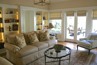 Diseño de sala de estar con biblioteca cerrada tradicional grande sin chimenea con paredes beige y suelo de madera clara