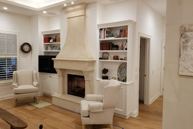 Foto de sala de estar con biblioteca abierta tradicional de tamaño medio con paredes blancas, suelo de madera clara, todas las chimeneas, marco de chimenea de hormigón, pared multimedia y suelo beige
