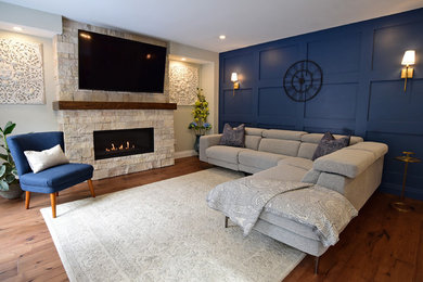 トロントにある中くらいなコンテンポラリースタイルのおしゃれなファミリールーム (青い壁、無垢フローリング、標準型暖炉、石材の暖炉まわり、壁掛け型テレビ、茶色い床) の写真