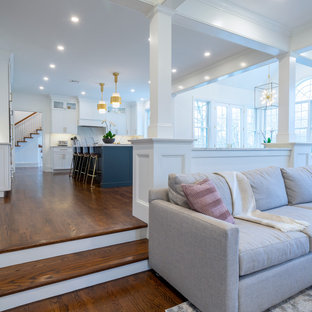 Großes, Offenes Klassisches Wohnzimmer mit weißer Wandfarbe, dunklem Holzboden, Kamin, Kaminumrandung aus Holz, Wand-TV, braunem Boden und Kassettendecke in Philadelphia
