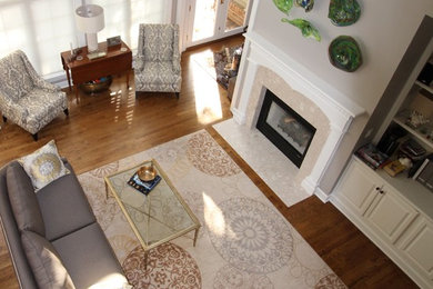 Modelo de sala de estar abierta clásica renovada de tamaño medio con paredes grises, suelo de madera en tonos medios, todas las chimeneas, marco de chimenea de baldosas y/o azulejos y pared multimedia