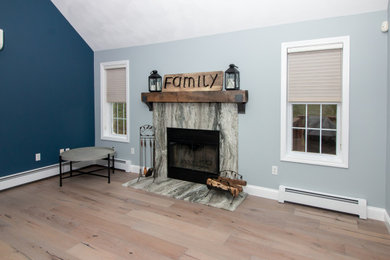 ボストンにあるお手頃価格の広いトランジショナルスタイルのおしゃれなファミリールーム (クッションフロア、標準型暖炉、石材の暖炉まわり、マルチカラーの床) の写真