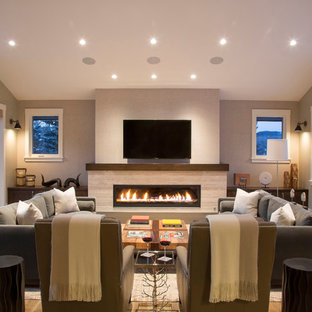 Example of a huge mountain style enclosed medium tone wood floor family room design in Denver with beige walls, a ribbon fireplace, a stone fireplace and a wall-mounted tv