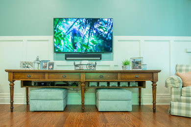 Modelo de sala de estar abierta clásica con paredes azules, suelo de madera oscura, televisor colgado en la pared y suelo marrón