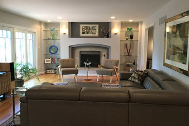 Foto de sala de estar abierta contemporánea grande con paredes grises, suelo de madera clara, todas las chimeneas, marco de chimenea de piedra y televisor independiente